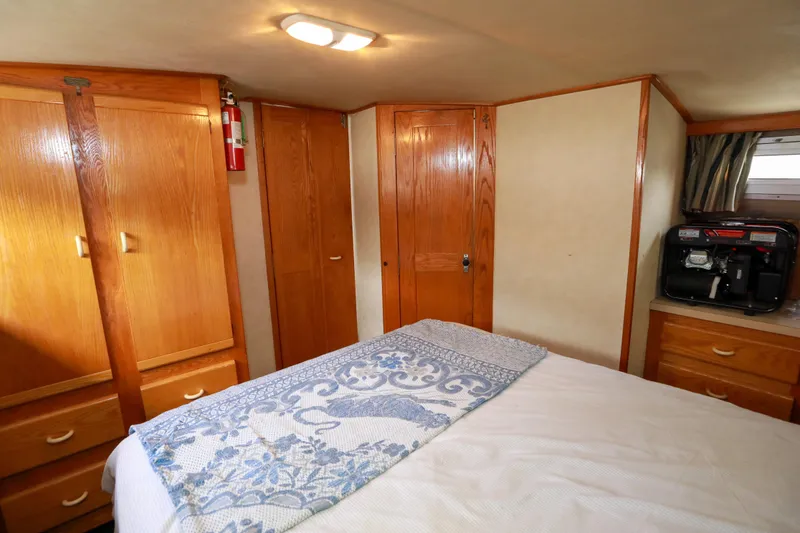 Slide: The Image of Cozy 1991 Silverton 41 Aft Cabin interior with bed, wooden cabinets, and nautical decor. - 25