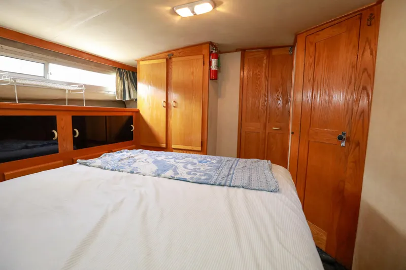 Slide: The Image of 1991 Silverton 41 Aft Cabin bedroom with wooden cabinets and cozy bedding. - 26