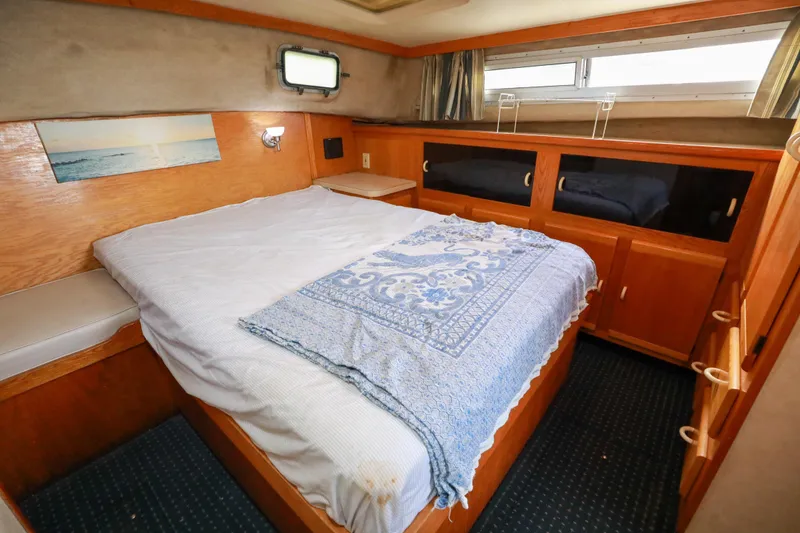 Slide: The Image of 1991 Silverton 41 Aft Cabin bedroom with wooden cabinetry and cozy bedding. - 27