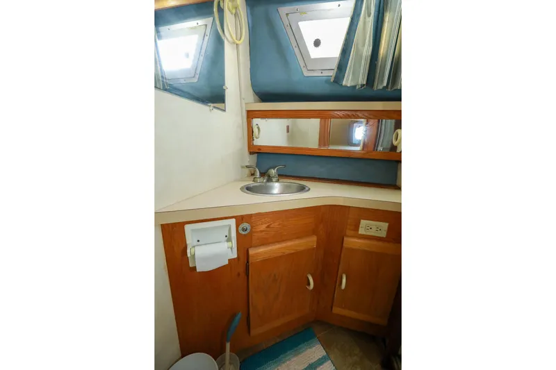 Slide: The Image of Interior of 1991 Silverton 41 Aft Cabin bathroom with sink, mirror, and striped curtains. - 31