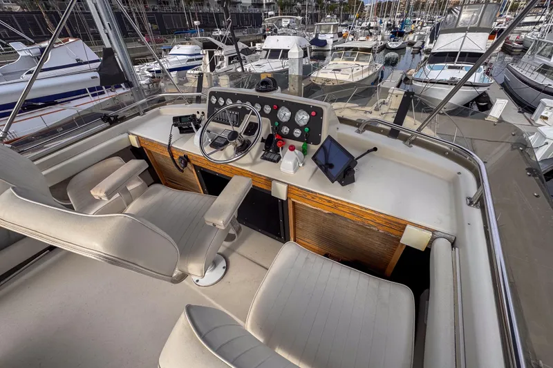 Slide: The Image of 1991 Silverton 41 Aft Cabin yacht helm with marina view, featuring navigation controls and seating. - 7