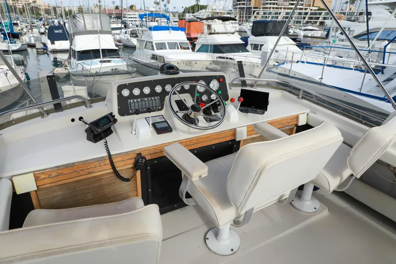 Slide: The Image of 1991 Silverton 41 Aft Cabin yacht helm with marina view, featuring navigation controls and seating. - 9