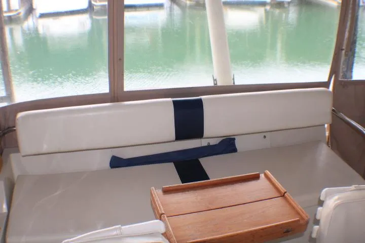 Slide: The Image of 1988 Tollycraft 30 Sport Cruiser interior with seating and wooden tray, overlooking marina. - 37