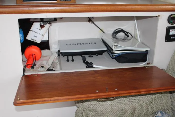 Slide: The Image of Open cabinet in 1988 Tollycraft 30 Sport Cruiser with Garmin device and boating accessories. - 49