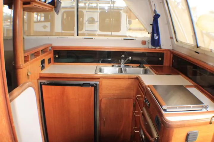 Slide: The Image of 1988 Tollycraft 30 Sport Cruiser interior with wooden cabinetry and compact kitchen area. - 55