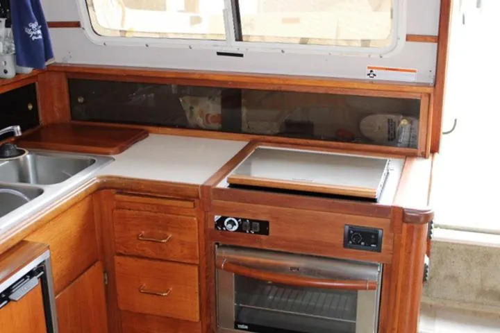 Slide: The Image of 1988 Tollycraft 30 Sport Cruiser kitchen with wooden cabinetry and modern appliances. - 57