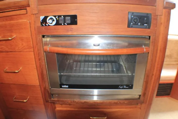 Slide: The Image of 1988 Tollycraft 30 Sport Cruiser interior with built-in oven and wooden cabinetry. - 60