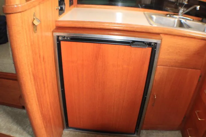 Slide: The Image of 1988 Tollycraft 30 Sport Cruiser interior with wooden cabinetry and compact kitchen area. - 61