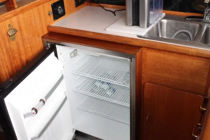 Slide: The Image of 1988 Tollycraft 30 Sport Cruiser galley with open fridge and sink. - 62