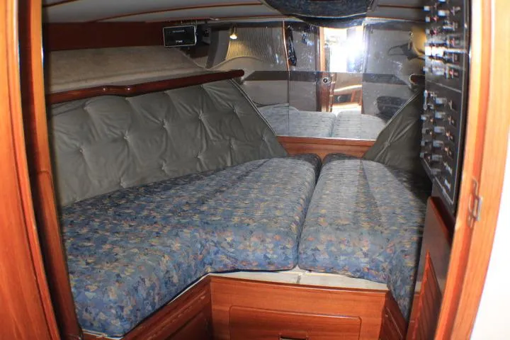 Slide: The Image of 1988 Tollycraft 30 Sport Cruiser cabin with blue patterned bedding and wood accents. - 64