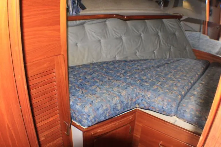 Slide: The Image of 1988 Tollycraft 30 Sport Cruiser cabin with blue-patterned bedding and wooden cabinetry. - 65