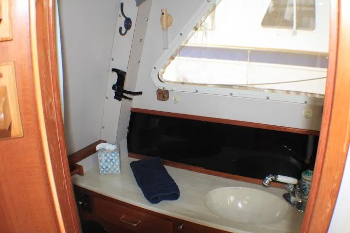 Slide: The Image of 1988 Tollycraft 30 Sport Cruiser bathroom with sink, window, and wooden cabinetry. - 69