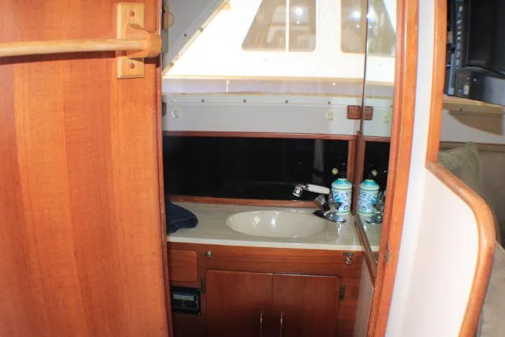 Slide: The Image of 1988 Tollycraft 30 Sport Cruiser interior with wooden cabinetry and sink area. - 70