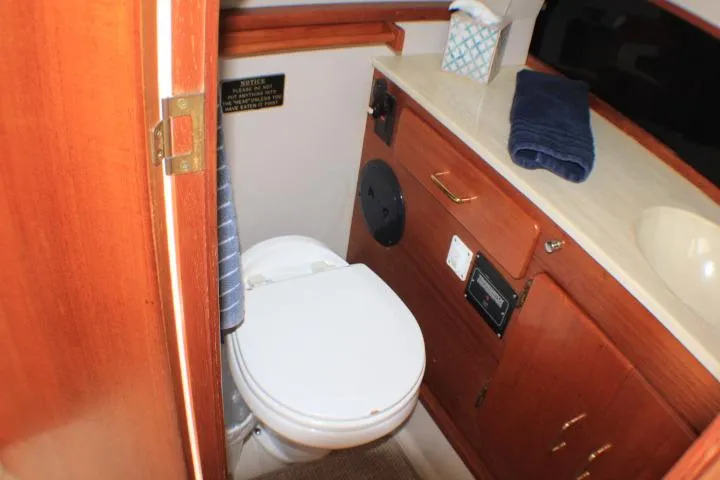 Slide: The Image of 1988 Tollycraft 30 Sport Cruiser bathroom with toilet, sink, and wooden cabinetry. - 73