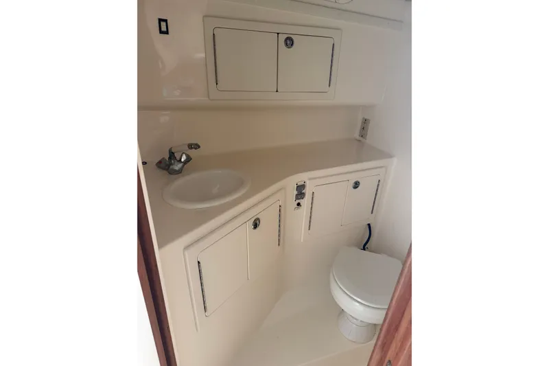 Slide: The Image of 2006 Carolina Classic 28 boat bathroom with sink, storage cabinets, and toilet. - 5