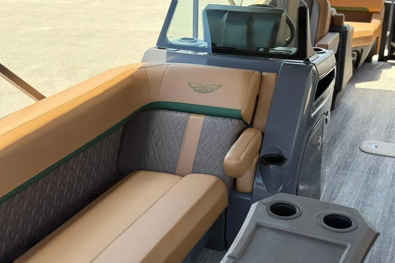 Slide: The Image of 2026 Bennington 24 M Quad Bench interior with tan and gray seating, cup holders, and console. - 17
