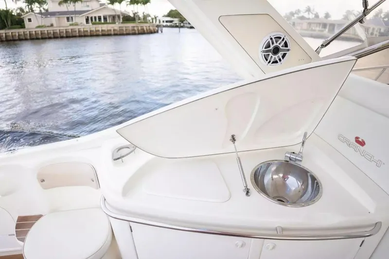 Slide: The Image of 1999 Cranchi Mediterranee 41 yacht with outdoor sink and speaker, docked by waterfront homes. - 9