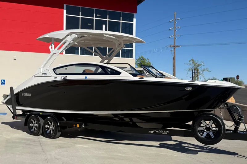The Image of 2024 Yamaha Boats 275SD, sleek black design, parked outdoors on a trailer. - 1