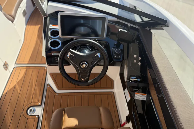 Slide: The Image of 2024 Yamaha Boats 275SD helm with steering wheel, touchscreen, and wood-style flooring. - 25
