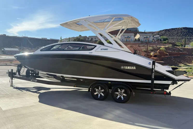Slide: The Image of 2024 Yamaha Boats 275SD on trailer, sleek black and white design, parked outdoors. - 6