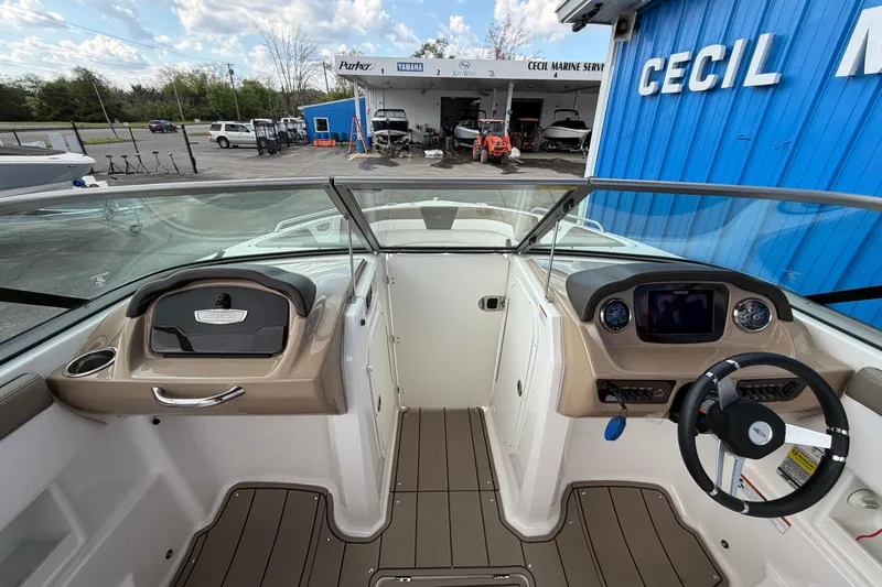 Slide: The Image of 2021 Chaparral 23 SSi boat interior with steering wheel and dashboard at a marina. - 11