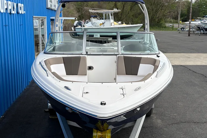 Slide: The Image of 2021 Chaparral 23 SSi boat with sleek design, parked outside a blue building. - 2