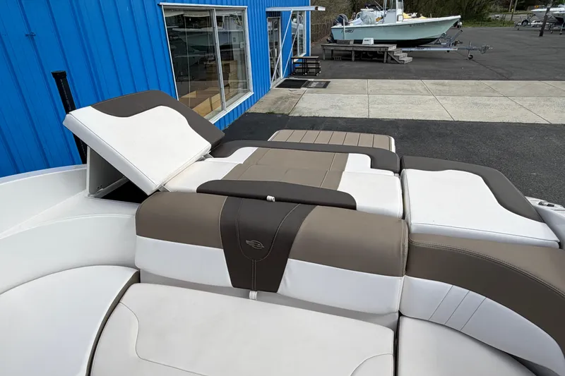 Slide: The Image of 2021 Chaparral 23 SSi boat interior with cushioned seating, docked near a blue building. - 28