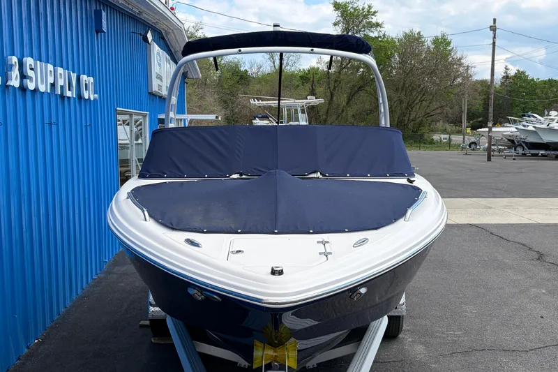 Slide: The Image of 2021 Chaparral 23 SSi boat with blue cover, parked outside a blue building. - 3