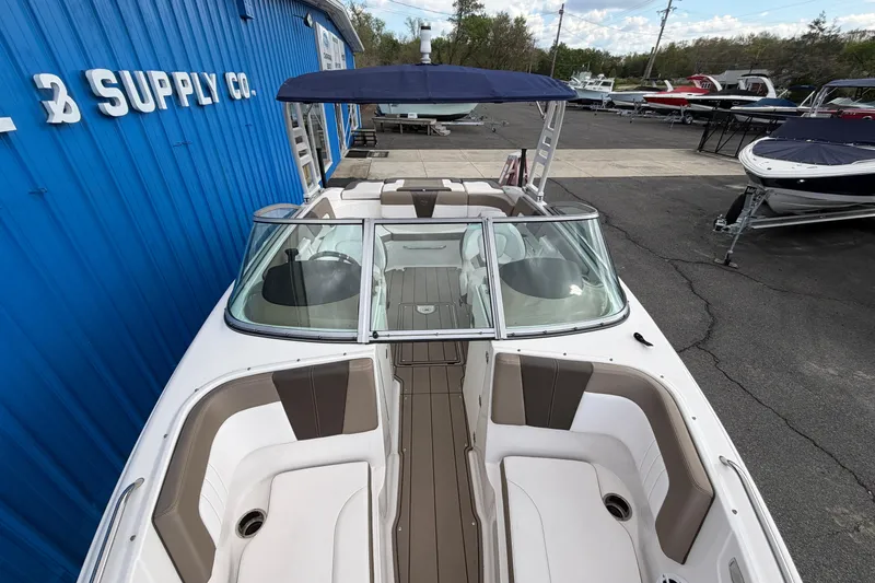 Slide: The Image of 2021 Chaparral 23 SSi boat with blue canopy, docked near a blue building. - 6