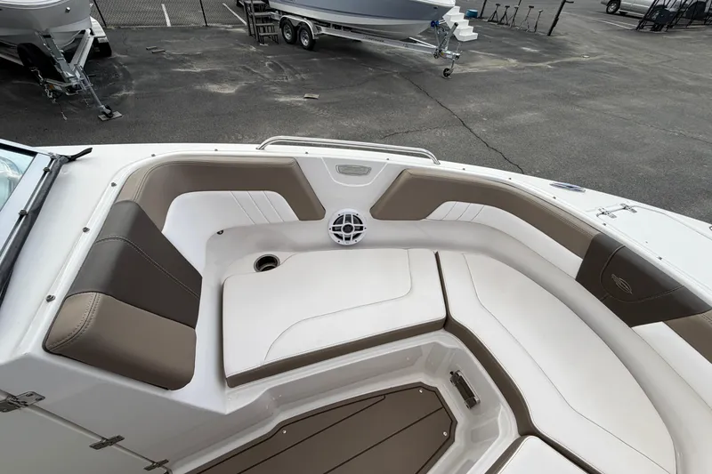Slide: The Image of 2021 Chaparral 23 SSi boat interior with white and brown seating, docked outdoors. - 8