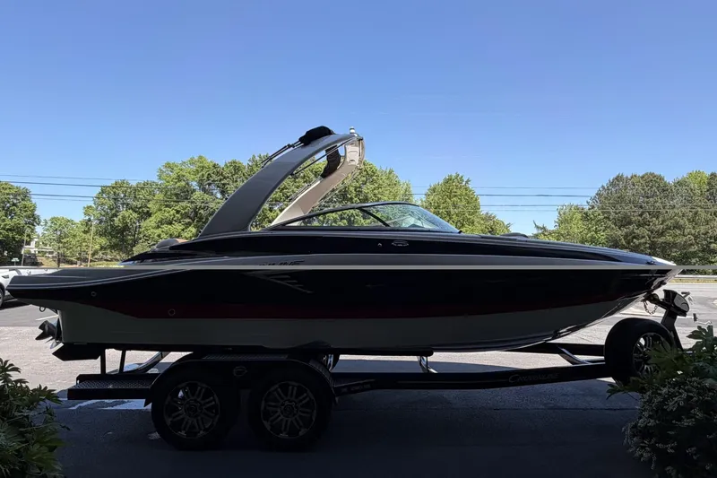 Slide: The Image of 2024 Crownline 260 SS boat on trailer, parked outdoors under clear blue sky. - 3