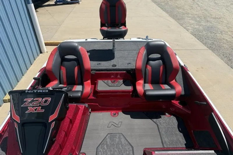 Slide: The Image of 2026 Nitro Z20 XL Pro boat interior with red and black seating, docked outdoors. - 22