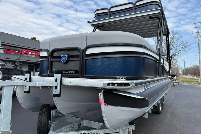Slide: The Image of 2025 Premier 250 Solaris Upper Deck - CL pontoon boat on trailer, outdoor setting. - 2
