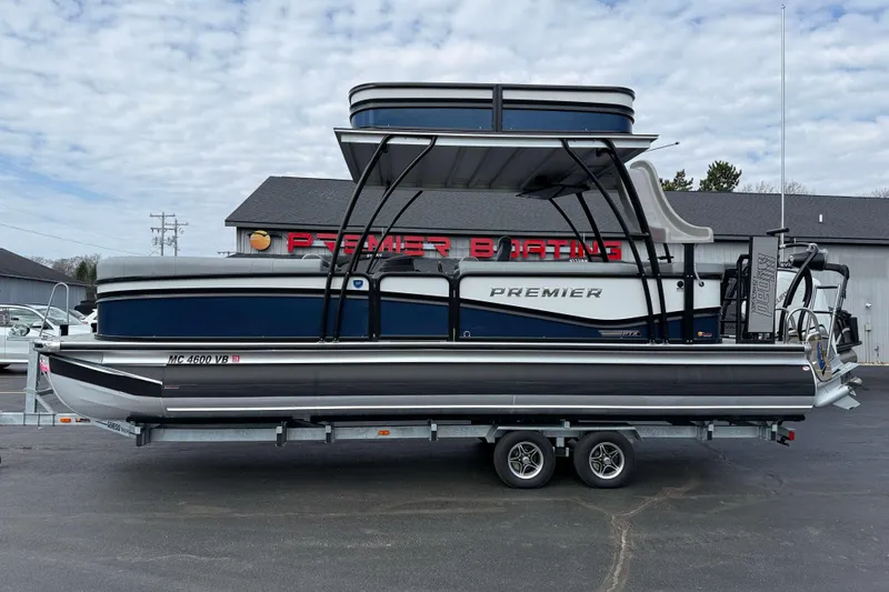 Slide: The Image of 2025 Premier 250 Solaris Upper Deck pontoon boat on trailer, parked outside dealership. - 3
