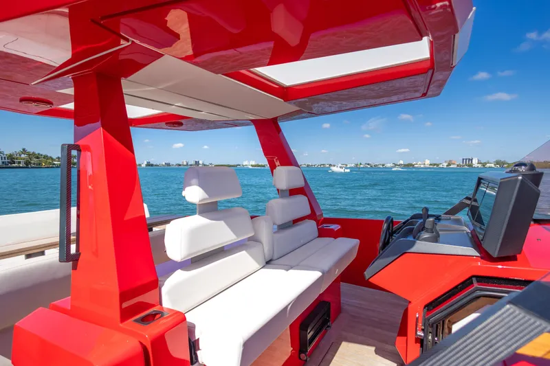 Slide: The Image of Red 2021 Wally 48 yacht interior with white seating, overlooking a scenic waterfront. - 28