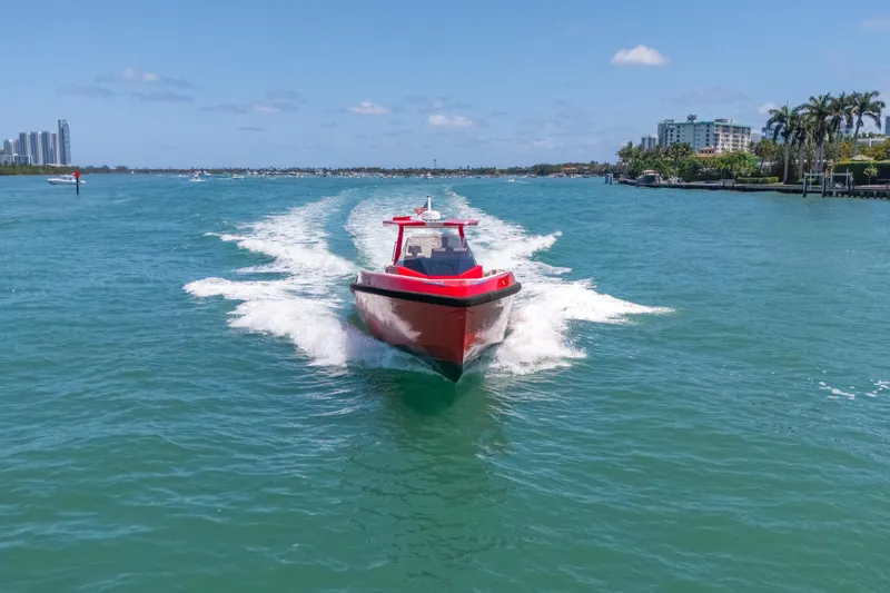 Slide: The Image of Red 2021 Wally 48 yacht cruising on clear blue water near a coastal city. - 5