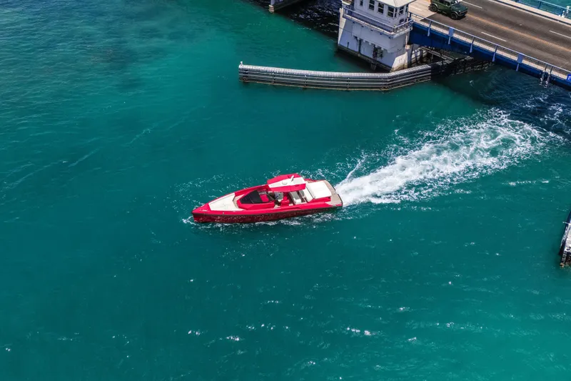 Slide: The Image of Red 2021 Wally 48 yacht cruising in turquoise waters near a bridge. - 8