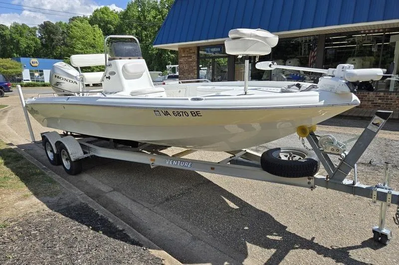 The Image of 2004 NauticStar 2200 NauticBay boat on trailer, parked outside a blue-roofed building. - 0