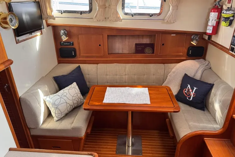 Slide: The Image of Cozy interior of 1999 Grand Banks 38 Eastbay EX with cushioned seating and wooden table. - 21