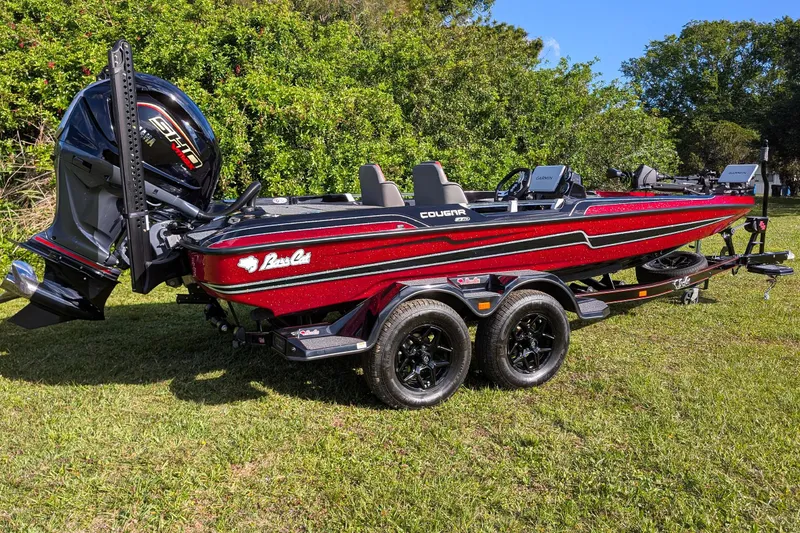 The Image of 2026 Bass Cat Cougar FTD boat on trailer, parked on grass, with lush greenery background. - 0