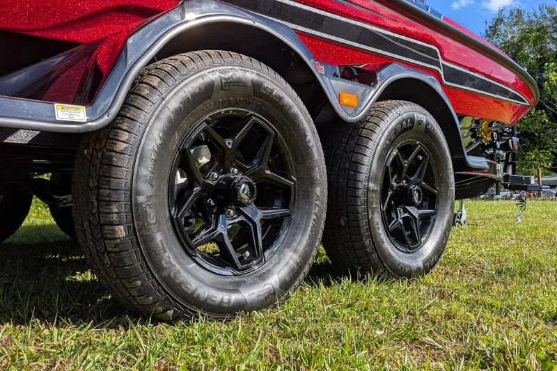 Slide: The Image of 2026 Bass Cat Cougar FTD trailer with black wheels on grass. - 10