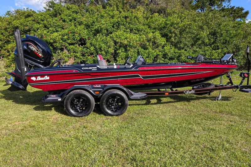 Slide: The Image of 2026 Bass Cat Cougar FTD boat on trailer, parked on grass with lush greenery background. - 3