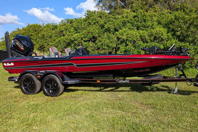 Slide: The Image of 2026 Bass Cat Cougar FTD boat on trailer, red and black design, parked on grass. - 4