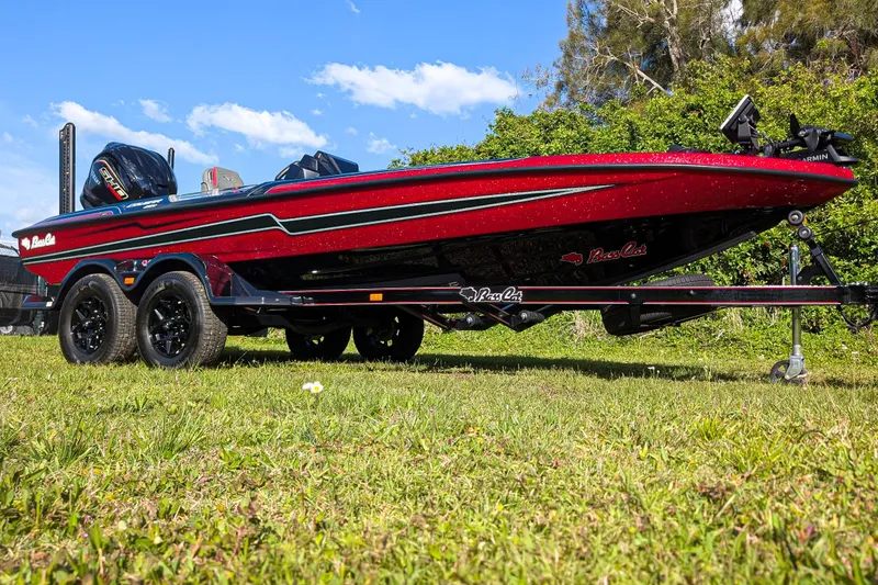 Slide: The Image of 2026 Bass Cat Cougar FTD boat on trailer, vibrant red and black design, parked on grass. - 7
