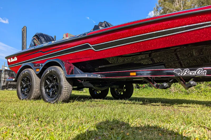 Slide: The Image of 2026 Bass Cat Cougar FTD boat on trailer, vibrant red finish, parked on grass. - 8