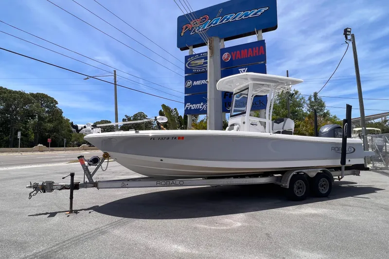 The Image of 2022 Robalo 246 Cayman boat on trailer at dealership, under clear blue sky. - 0