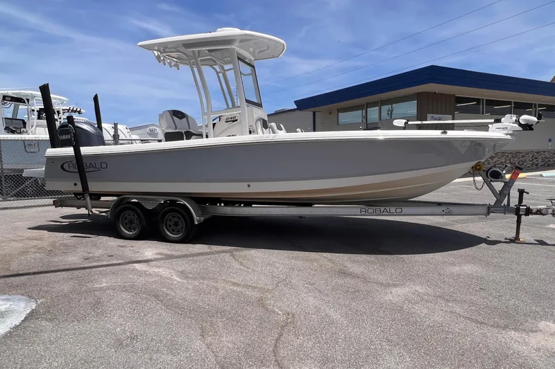 Slide: The Image of 2022 Robalo 246 Cayman boat on trailer, parked outdoors under clear sky. - 2