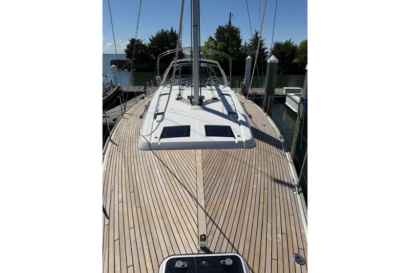 Slide: The Image of 2016 Beneteau Oceanis 48 sailboat with teak deck, docked in a serene marina setting. - 10