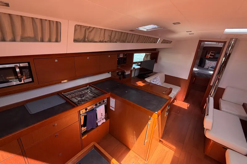 Slide: The Image of Interior of 2016 Beneteau Oceanis 48 yacht, featuring modern kitchen and cozy seating area. - 24