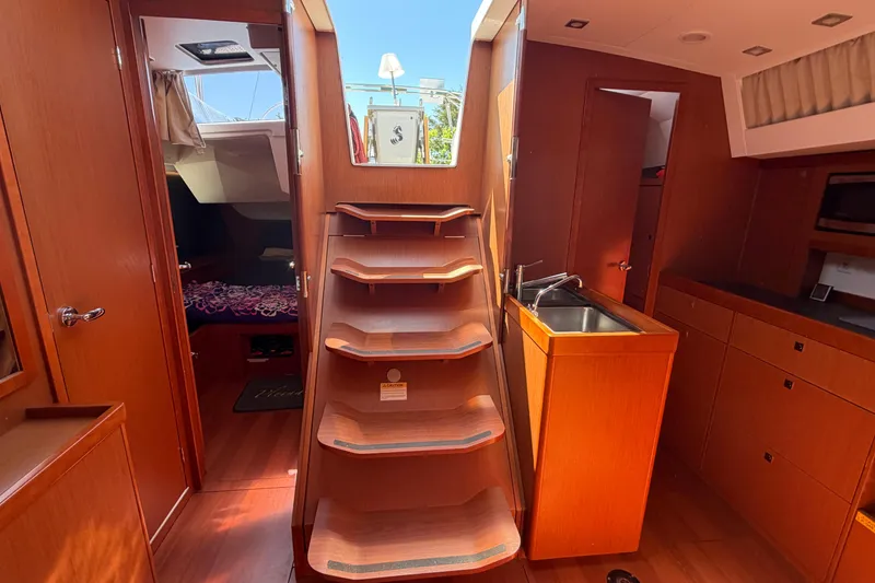 Slide: The Image of Interior of 2016 Beneteau Oceanis 48 yacht with wooden stairs and compact kitchen area. - 28
